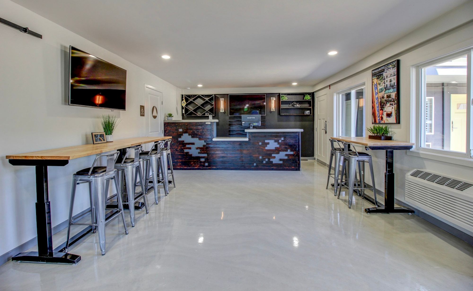 Modern, sleek bar area with high stools, glossy dark front, and bright, airy seating along windows. Always ends with a period.